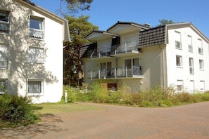 A multi-story residential building with balconies, a paved driveway, and surrounding greenery. - House "An der Düne" Apartment C-9 (Seebad Heringsdorf)