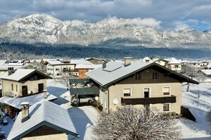 A residential area with houses, some with snow-covered roofs, and a mountain range in the background. - Holiday apartment with 2 bedrooms (Angath)