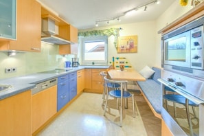 A compact kitchen with a dining area, a coffee machine, and a refrigerator. - Holiday apartment with 2 bedrooms (Angath)