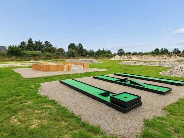 Ein grünes Areal im Freien mit mehreren Minigolfbahnen und einer Holzkonstruktion.