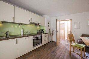 A modern kitchen with white cabinets, a stainless steel range hood, and a wooden countertop. - Holiday apartment with 2 bedrooms (Ramsau im Zillertal)