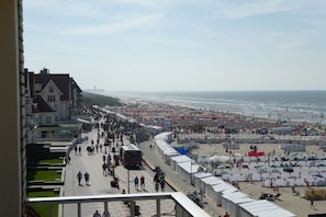 Een kustpromenade met strand, gebouwen en een heldere lucht.