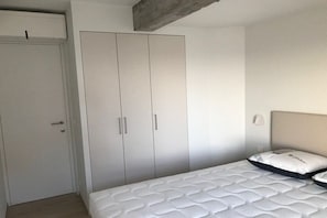 Een slaapkamer met een bed, een kledingkast en een deur.