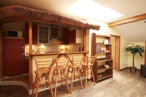 A compact kitchen with a thatched roof, wooden chairs, and a small dining table. - Holiday apartment in Saal with swimming pool (Saal)