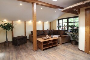 A cozy room with a wooden ceiling, a sofa, a coffee table, and a large window with a view of greenery. - Holiday apartment in Saal with swimming pool (Saal)