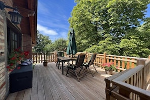A wooden deck with a table and chairs, surrounded by a wooden railing and potted plants. - Holiday apartment in Saal with swimming pool (Saal)