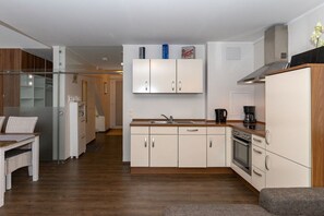 A modern kitchen with white cabinets, a built-in oven, and a coffee maker. - Holiday apartment with 1 bedroom (Kühlungsborn)
