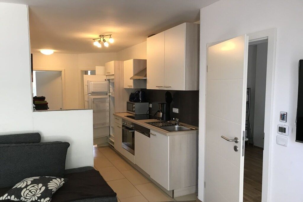 A compact kitchen with white cabinets, a built-in oven, and a coffee machine.
