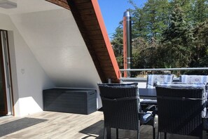 Un balcó amb dues cadires de vimet, una taula i una barbacoa.