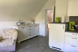 A compact kitchen with white cabinetry, a small dining area with a chair, and a bicycle on the counter. - Holiday apartment with 1 bedroom (Struppen)