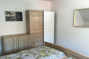 Een slaapkamer met een bed, een kledingkast en een spiegel.