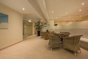 A modern indoor area with wicker furniture, a potted plant, and a tiled floor. - Vrbo Property (Zempin)