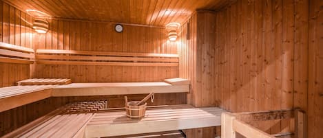 Una sauna con bancos de madera y un balde.