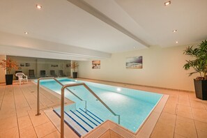 An indoor swimming pool with clear blue water, tiled walls, and a modern design. - Vrbo Property (Zempin)