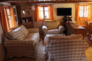 A cozy living room with checkered sofas, a wooden cabinet, and a television mounted on the wall. - Alpine cabin with 3 bedrooms (Horní Maršov)