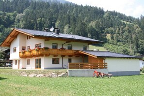 Ein zweistöckiges Gebäude mit Balkon, Satellitenschüssel und kleinem Garten.