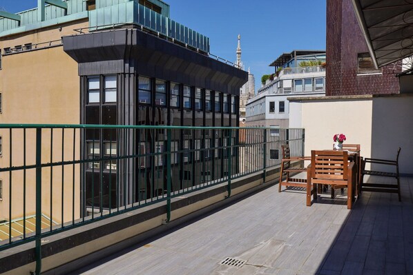 A balcony with a table and chairs, a metal railing, and a view of adjacent buildings. - Contempora - Cavallotti 13 - Two-room apartment with a terrace on the top floor - A64 (Milano)