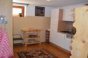 A compact kitchen with white cabinets, a wooden countertop, a sink, and a small wooden table with baskets. - Holiday apartment with 2 bedrooms (Baldramsdorf Kärnten)