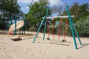 A playground with a swing set and a climbing structure. - Beach House Dune Nest (Fehmarn)