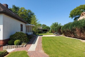 Il s’agit d’une propriété résidentielle dotée d’une pelouse bien entretenue, d’un chemin en briques menant à la maison et d’un espace patio aménagé avec du mobilier d’extérieur.