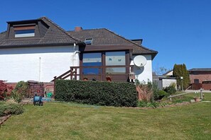 A two-story house with a satellite dish, a wooden deck, and a well-maintained garden. - Holiday apartment with 2 bedrooms (Steinberg)