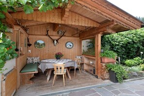 A wooden outdoor seating area with a table and chairs, surrounded by a wooden structure with a sloped roof. - Holiday apartment in Hippach with Wi-Fi (Hippach)