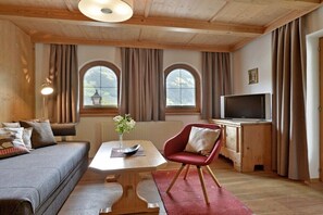 A cozy room with a sofa, a red chair, a wooden table, and a TV. - Holiday apartment in Hippach with Wi-Fi (Hippach)