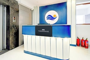 Een receptiebalie met een bord waarop 'TOWNHOUSE' staat en een logo erboven. Drie brandblussers aan de rechterkant.