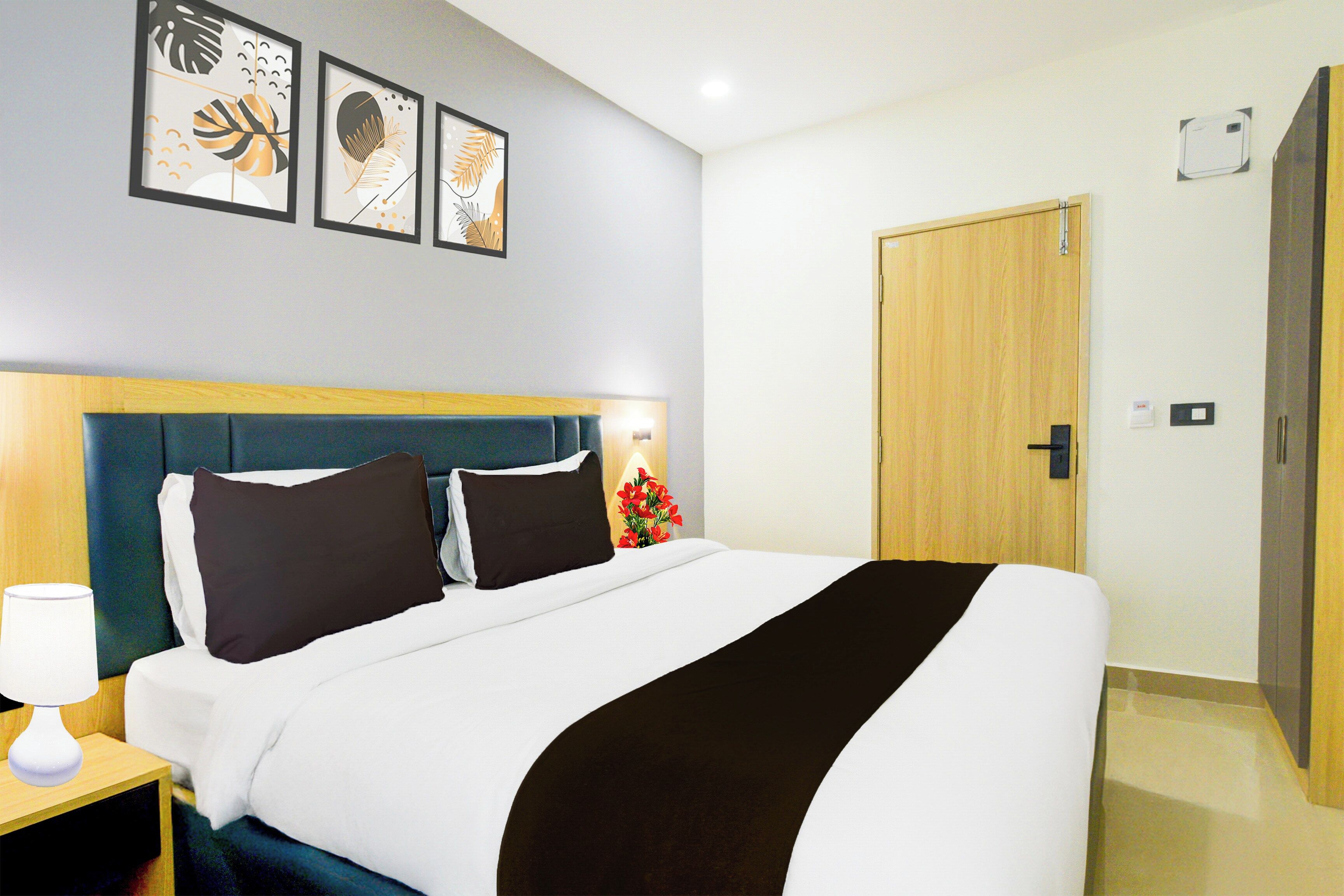 A hotel room with a bed, a nightstand, a lamp, and a door.