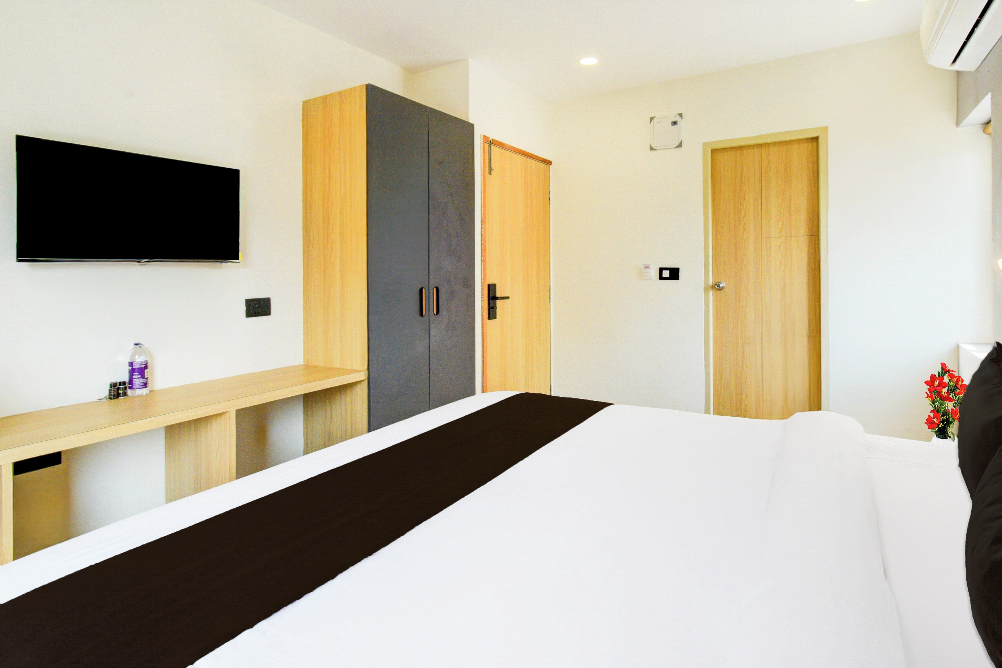 Quarto moderno com cama, televisão, guarda-roupa e escrivaninha.
