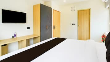 Quarto moderno com cama, televisão, guarda-roupa e escrivaninha.