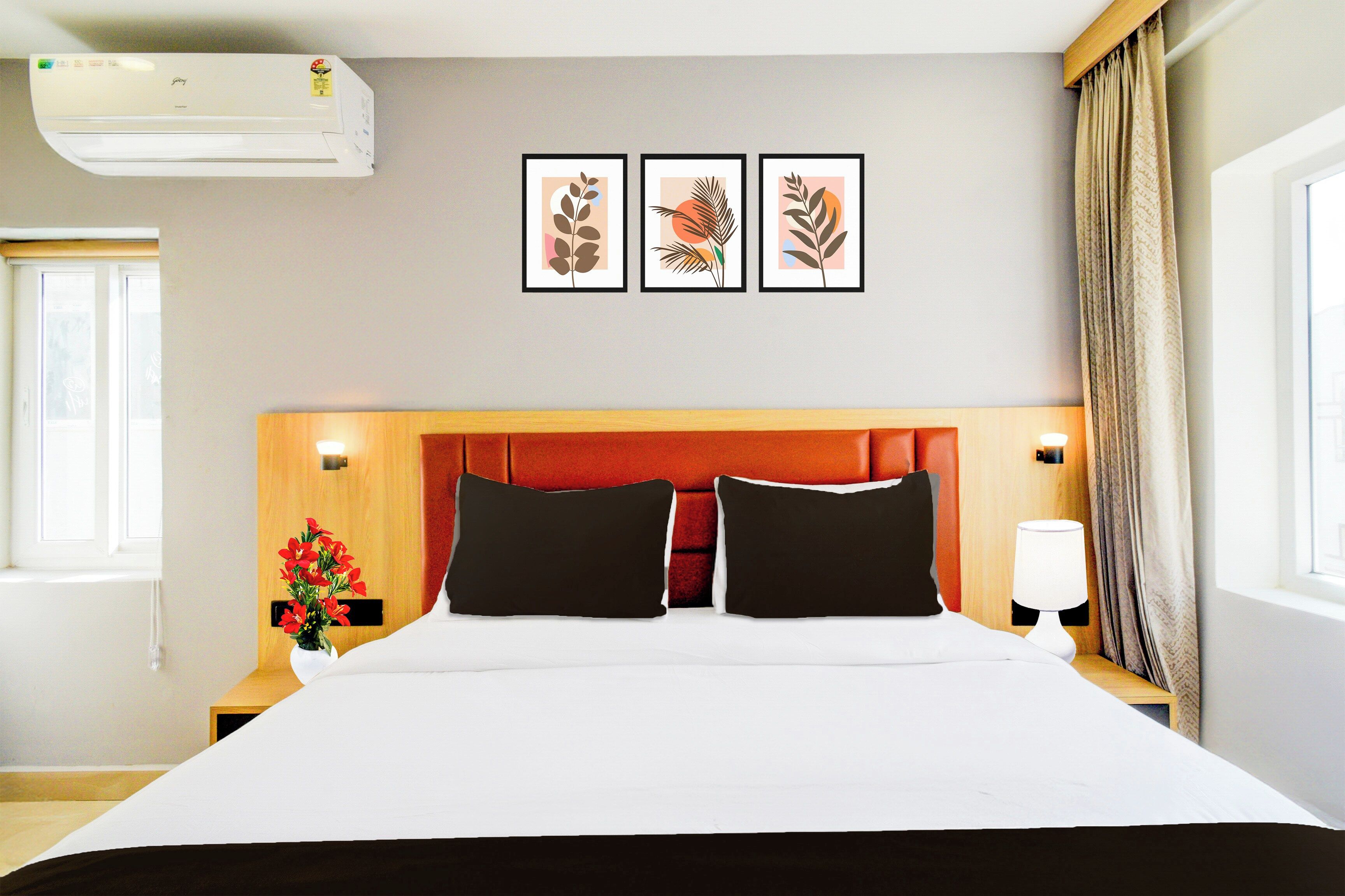 Una habitación de hotel con cama, mesita de noche, lámpara, ventana con cortinas y decoración en la pared.