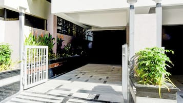 Um pátio com piso de azulejos, um portão branco e vasos de plantas.