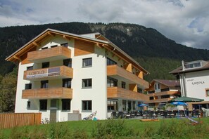 A multi-story building with balconies, a sign that reads 'Laijola,' and a view of a mountainous landscape. - Apartment Laijola III (Gaschurn)