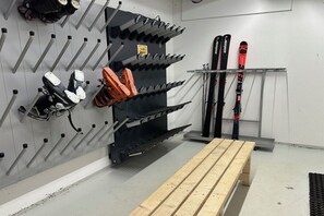 A ski storage area with racks for skis and boots, a bench, and a wall-mounted ski rack. - Apartment Laijola III (Gaschurn)
