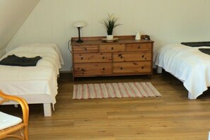 A bedroom with two beds, a wooden dresser, a lamp, a potted plant, and a striped rug. - "Frieda" holiday paradise under thatch (Damp)
