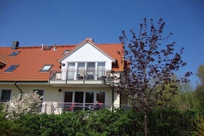 A two-story building with a red-tiled roof, a balcony with outdoor furniture, and a clear sky. - "Sea Breeze", 50 m from the beach (Insel Poel \/Schwarzer Busch)