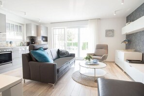Ein modernes Wohnzimmer mit einer Couch, einem Couchtisch und einem Essbereich mit Tisch und Stühlen.
