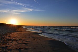 A beach with the sun setting over the horizon, waves gently lapping at the shore, and a clear sky. - Holiday home with 3 bedrooms (Zinnowitz)