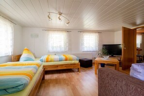 Ein Zimmer mit zwei Betten, einem Fernseher, einem Tisch und einem Fenster.