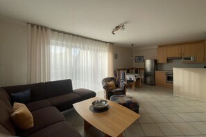 A living room with a sofa, a coffee table, and a dining area with chairs. - Holiday home with 2 bedrooms (Kaltenhof)