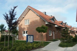 A brick building with a sloped roof, a signboard, and a pathway leading to it. - Holiday home with 2 bedrooms (Kaltenhof)