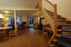 A spacious living area with a wooden staircase, a dining table, and a sofa. - Holiday home Fehmarn-farm (Fehmarn)