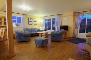 A cozy living room with a sofa set, ottoman, and a flat-screen TV. - Holiday home Fehmarn-farm (Fehmarn)