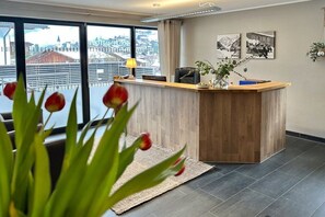 A reception desk with a view of a cityscape through large windows. - Apartment Laijola II (Gaschurn)
