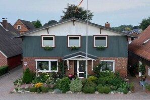 Un immeuble résidentiel à deux étages, doté d’une façade symétrique, d’une entrée centrale et d’un petit jardin à l’avant.