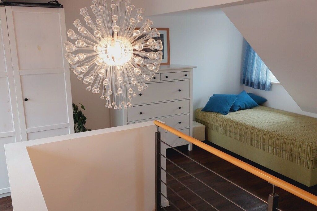 A bedroom with a bed, a dresser, and a unique chandelier.