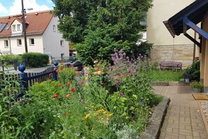En have med forskellige blomster og en bænk.