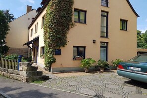 En toetages bygning med en facade af sten, en bil foran og en belagt indkørsel.