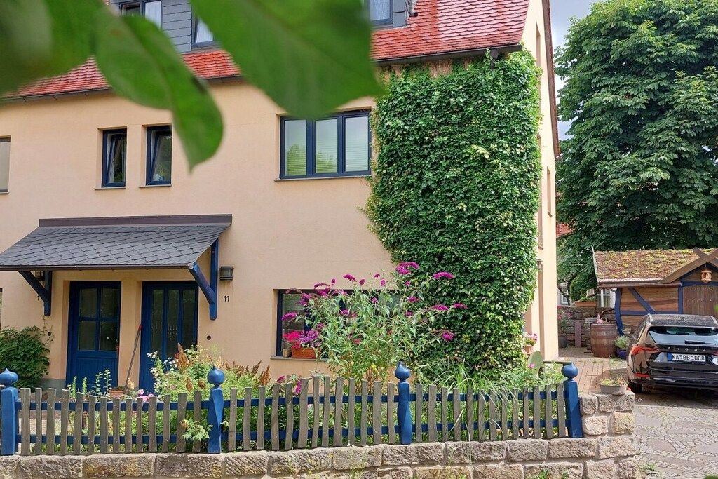 A residential building with a blue door, a stone wall, and a car parked in front.